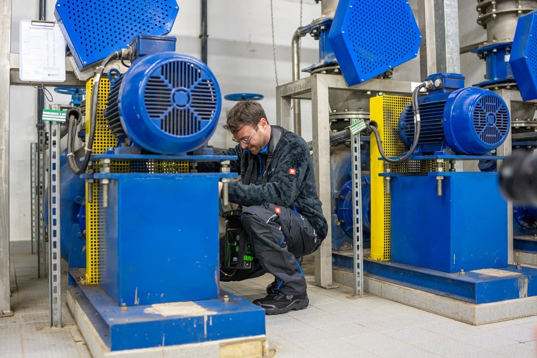 Ein Mann arbeitet in einer Fabrik an einer blauen Maschine.