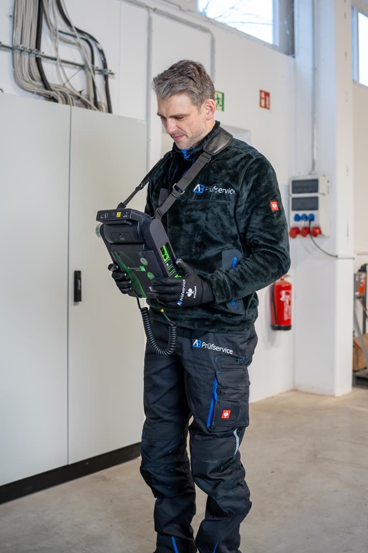 Ein Mann steht in einer Garage und hält ein Tablet in der Hand.